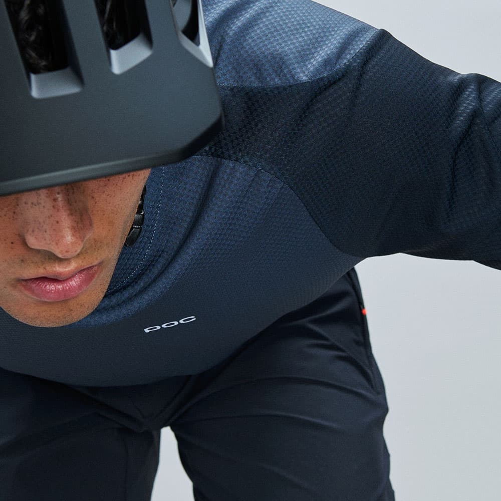 Person wearing a black helmet and dark cycling gear, leaning forward in a riding position, with a focus on the upper body and helmet.