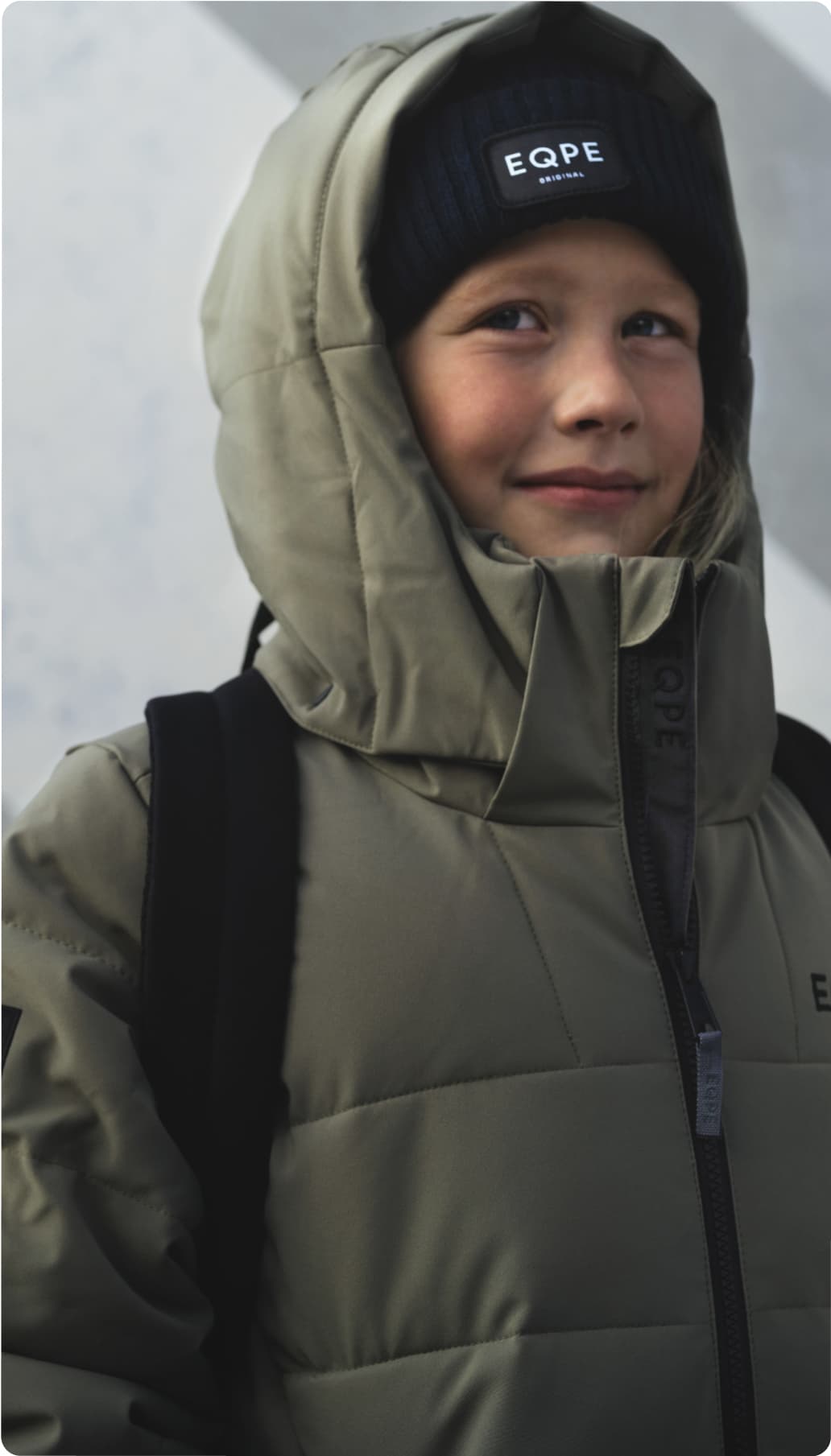 Child in a green winter coat and black beanie.