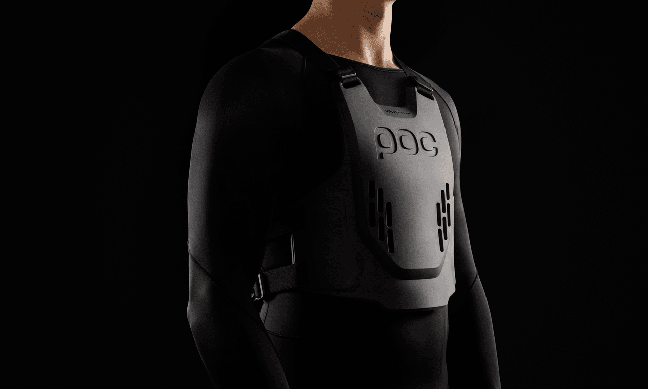 Person wearing a sleek, black protective vest against a dark background, highlighting its modern design and fit.