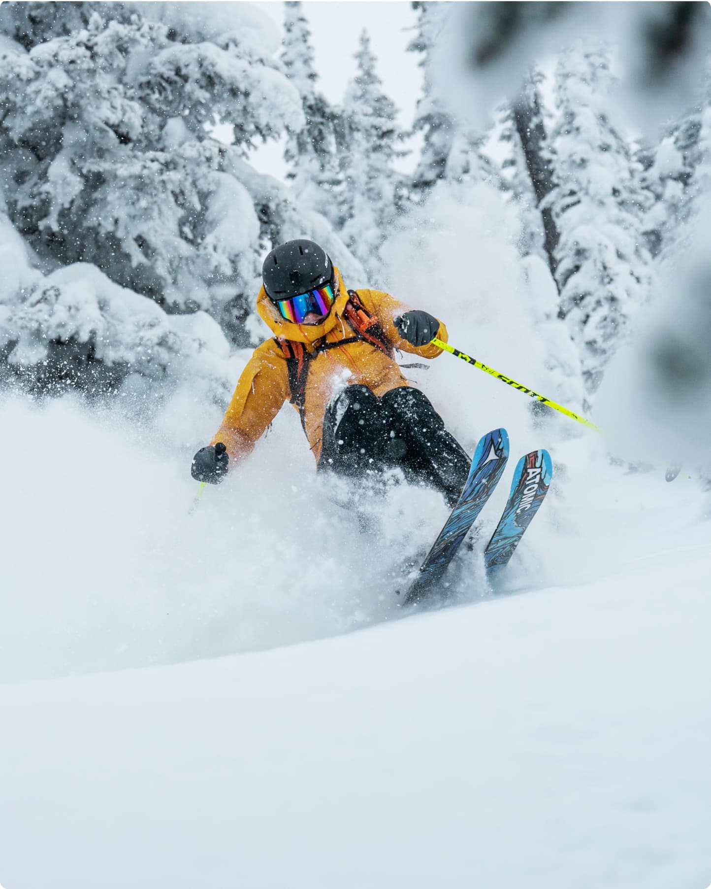 Skier in an yellow ski jacket navigating through deep snow, surrounded by snow-covered trees.