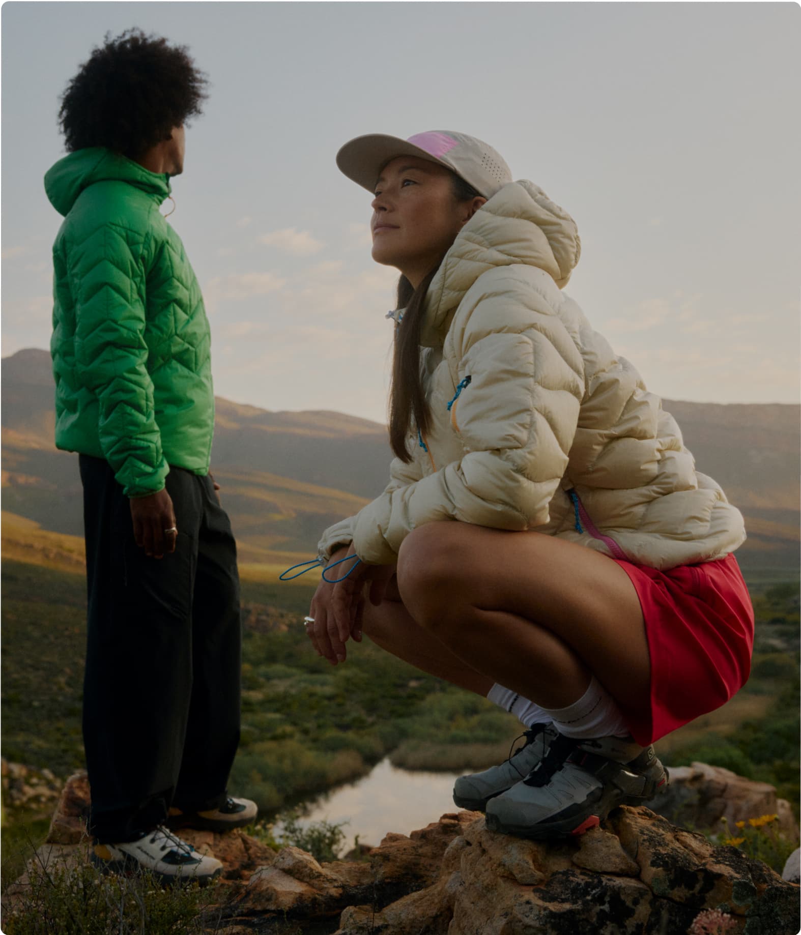 Two people in puffer jackets enjoy a scenic mountain view.
