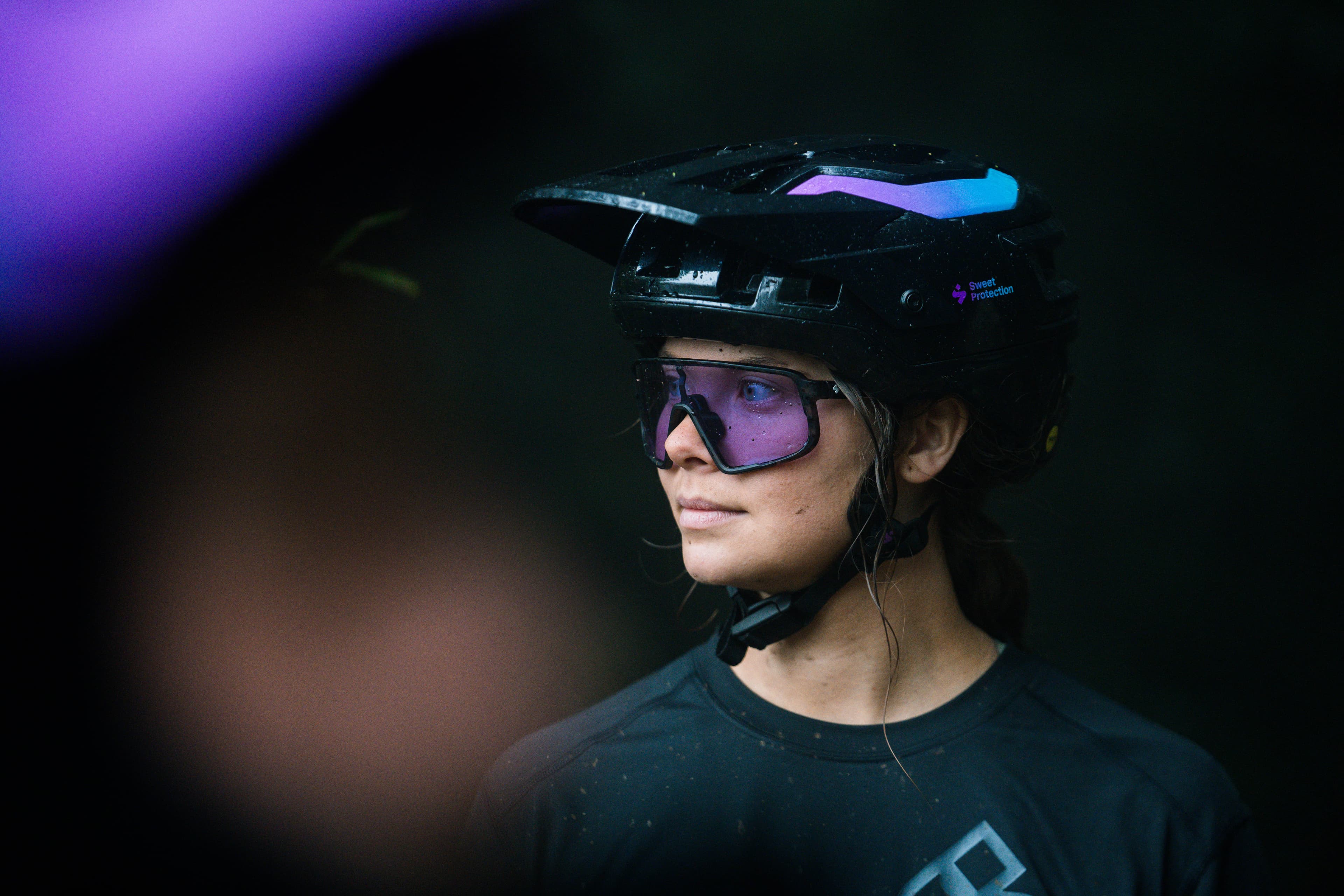 Close-up picture of a girl wearing a mountain bike helmet and glasses, looking to the side