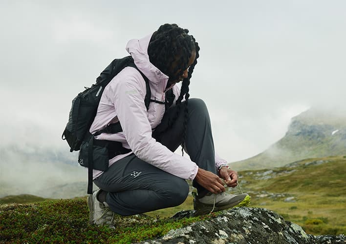 A woman in mountain terrain tying her hiking boot
