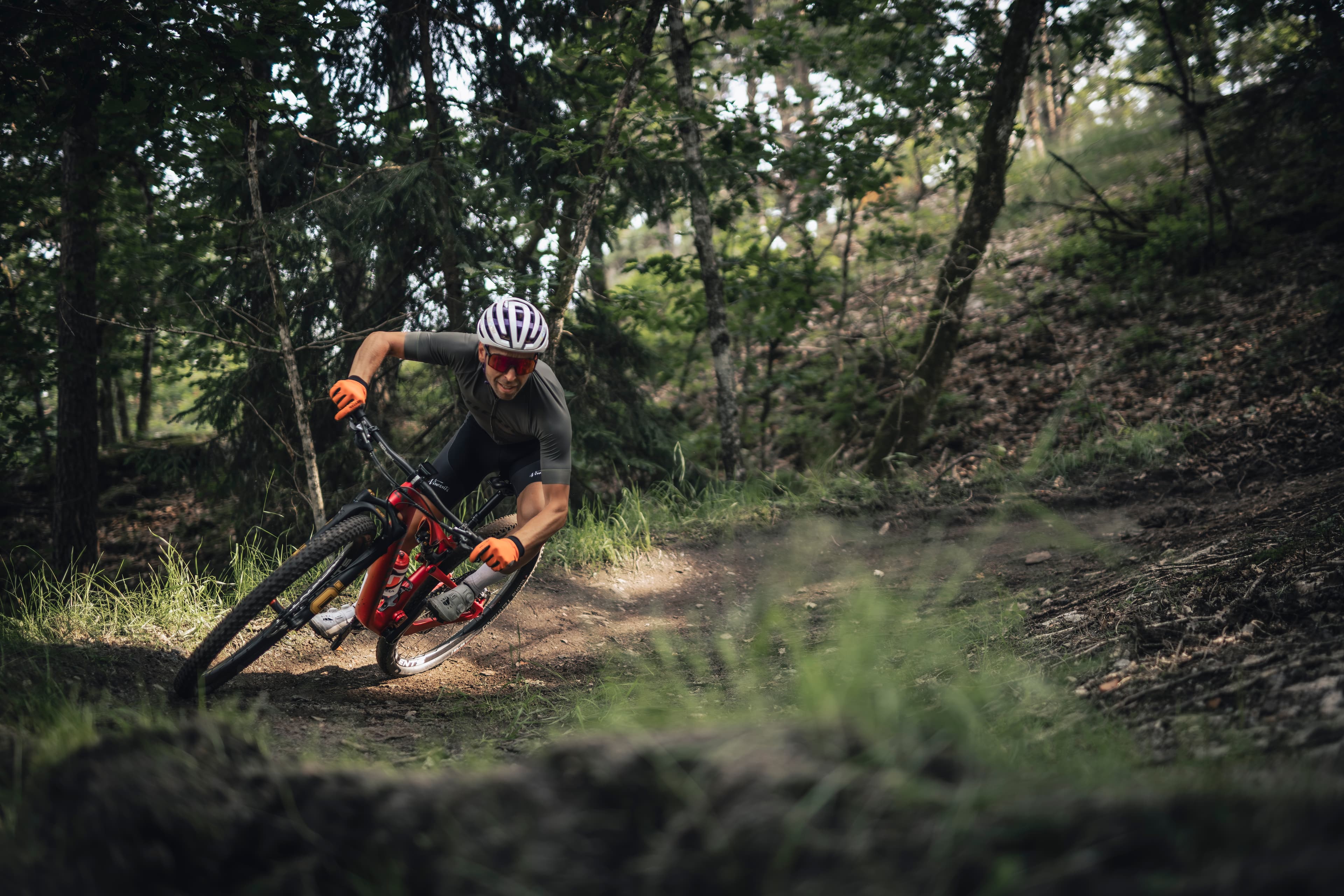 A man riding a mountain bike on a downhill track in the forest.