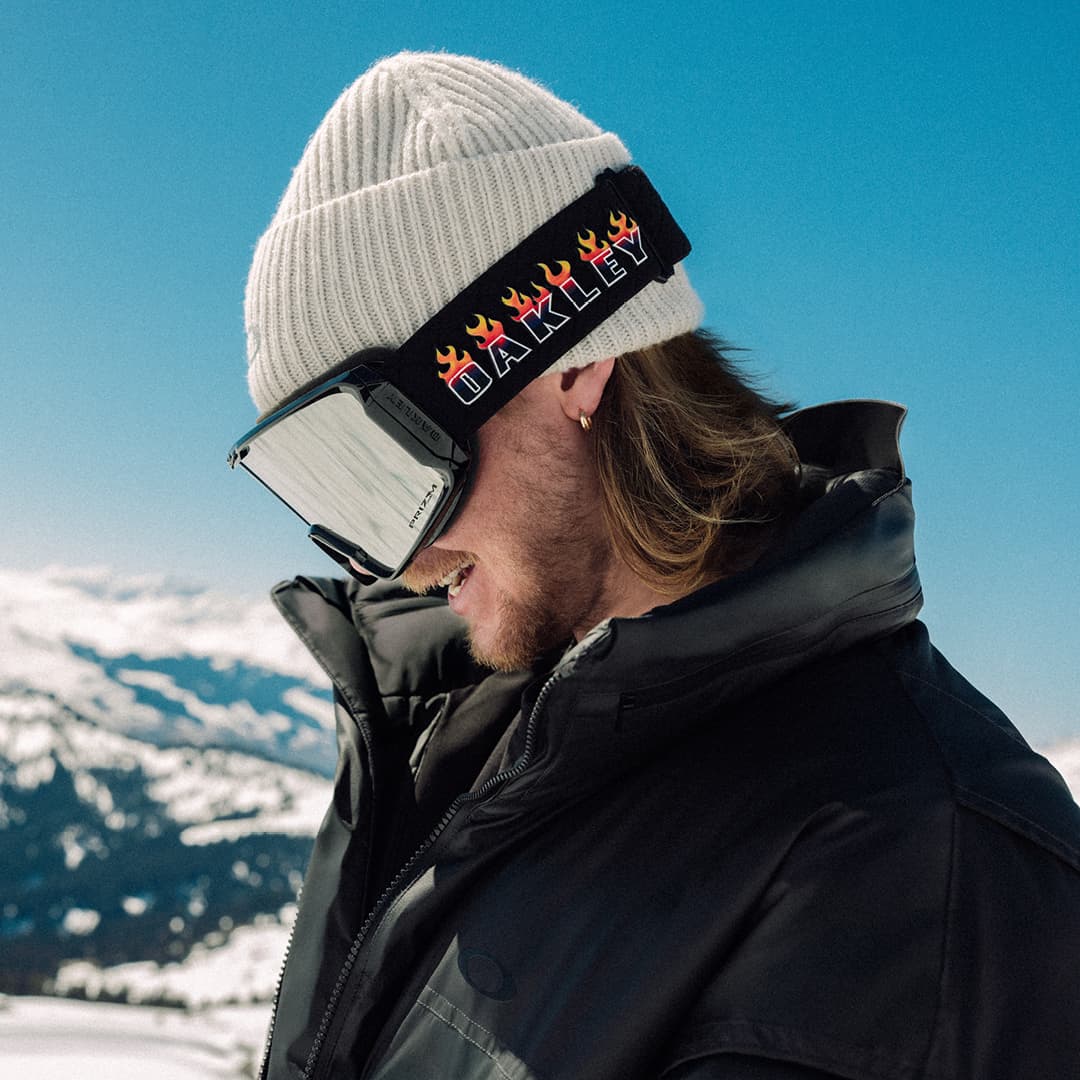 Man wearing Oakley goggles with mountains and blue sky in the background