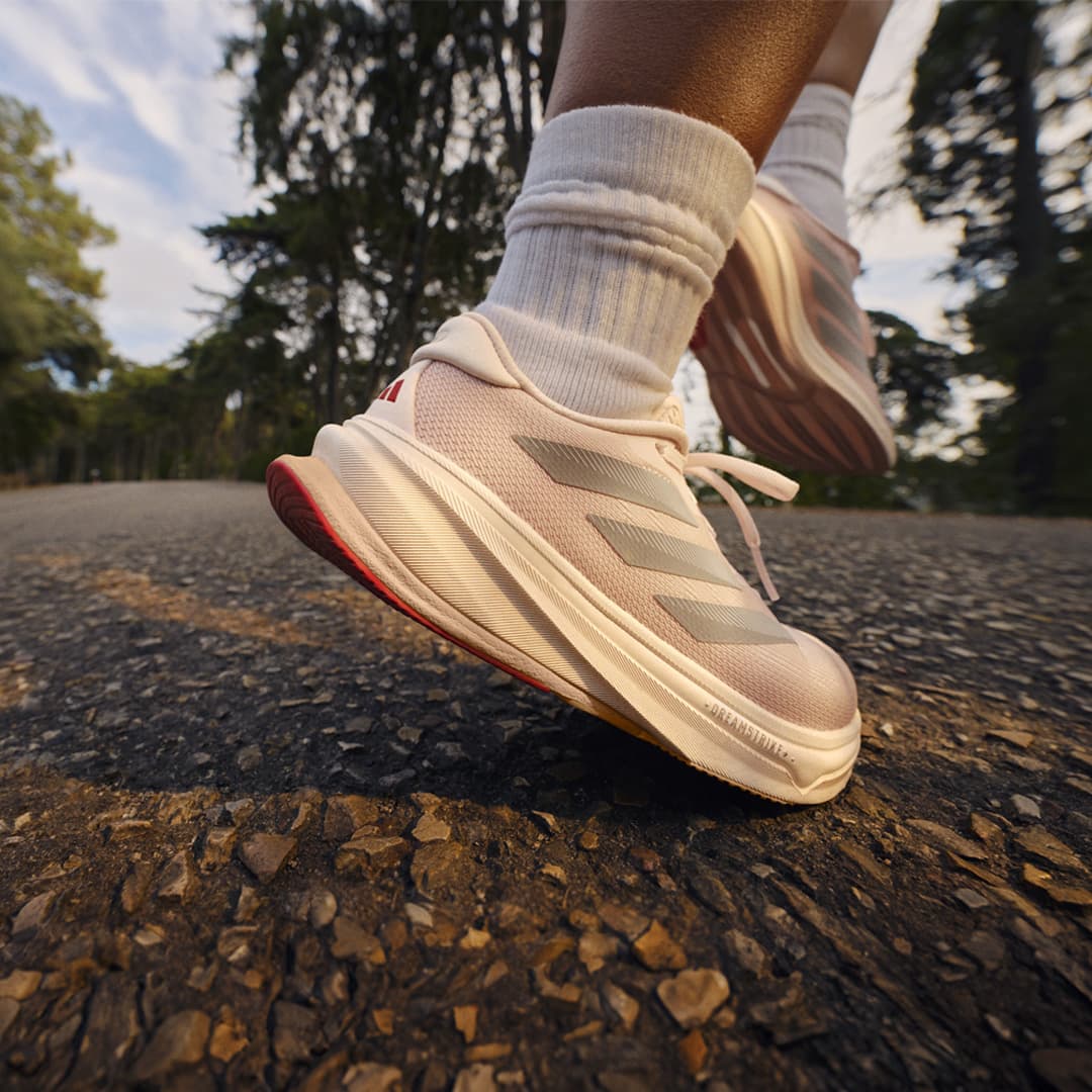 Close-up of a person wearing running shoes and white socks, on a textured surface.