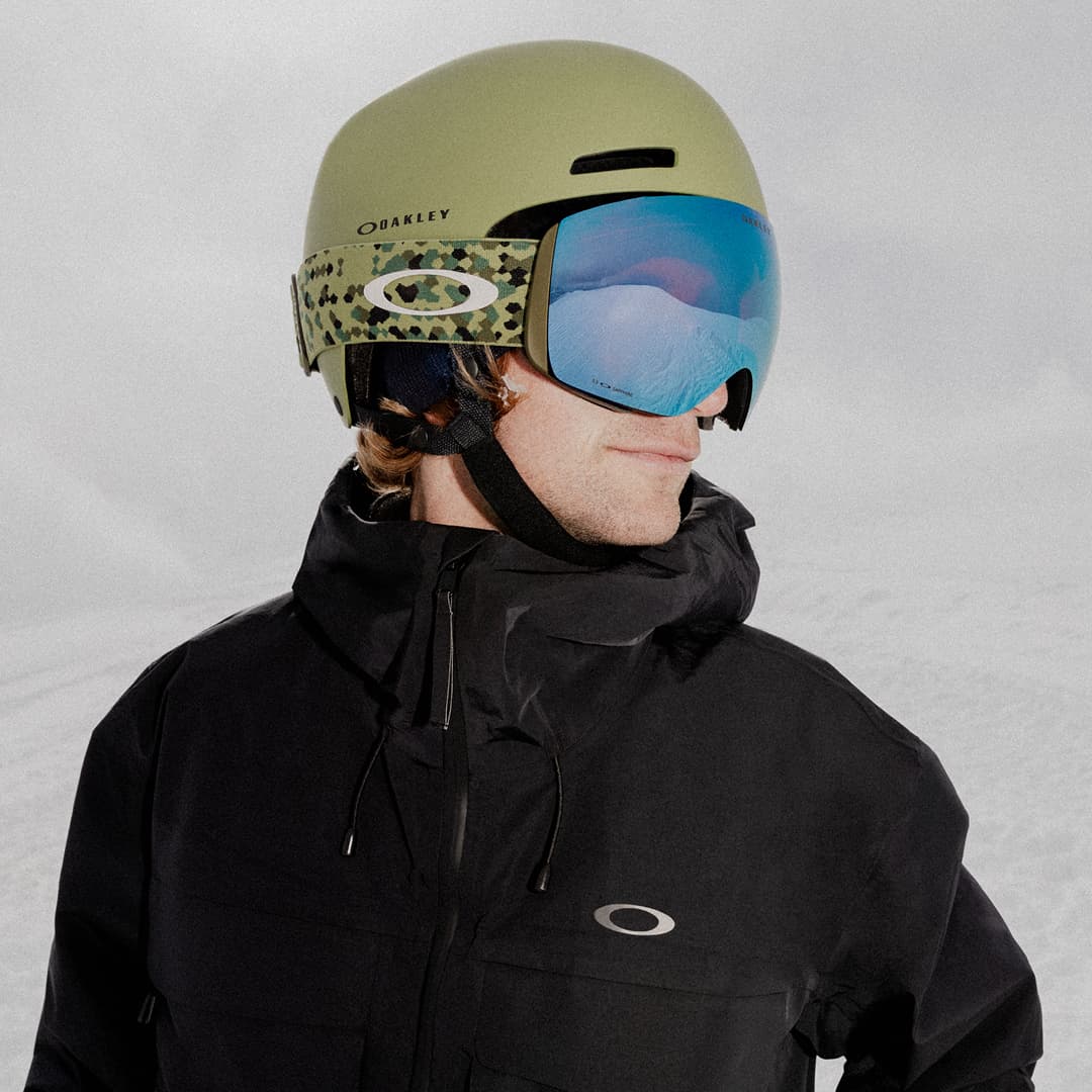 Man wearing Oakley goggles, helmet and jacket against snowy background