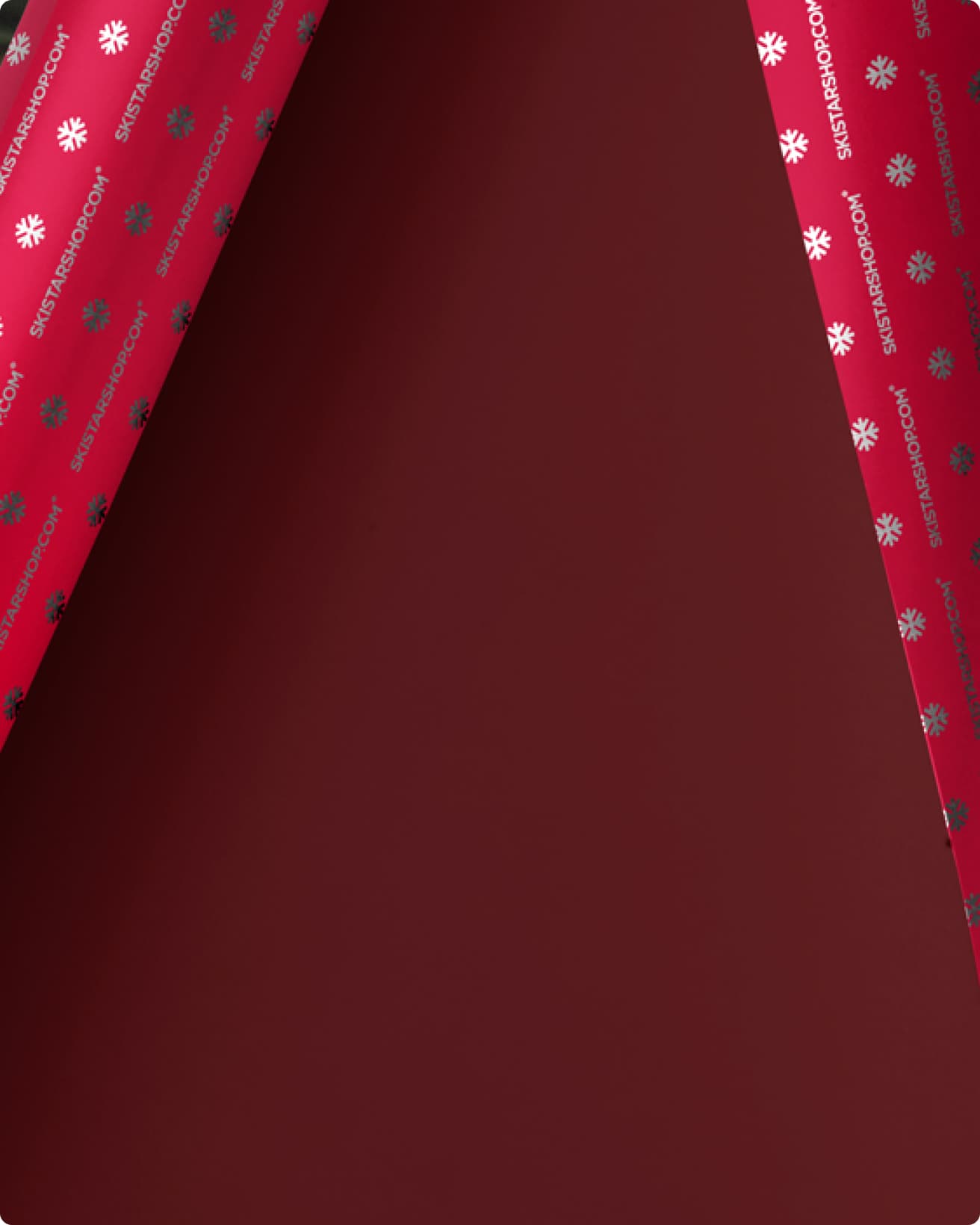 Red wrapping paper with a folded corner, revealing a pattern of white snowflakes.