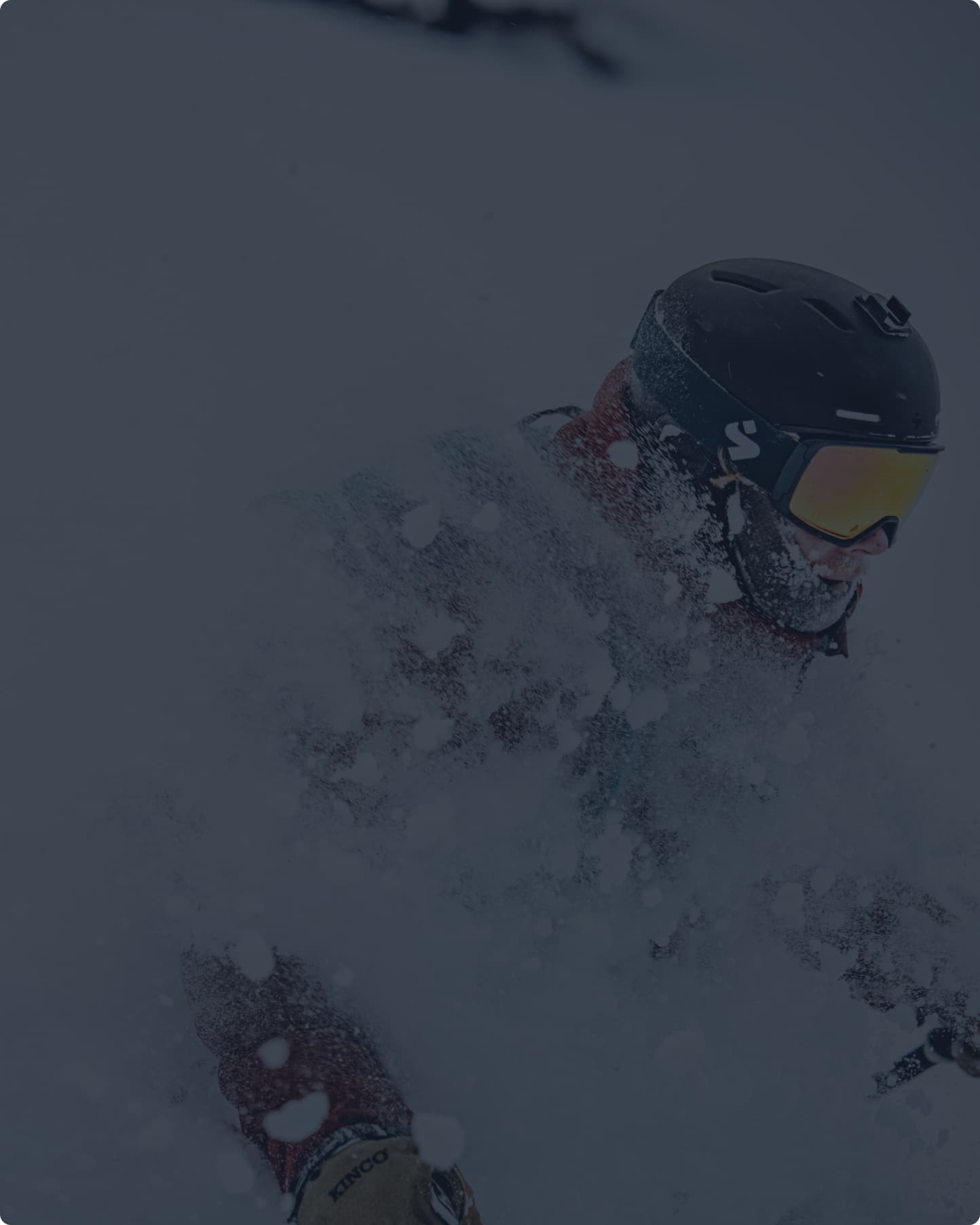 A skier rides through deep powder snow.  Snow is spraying up, partially obscuring the skier.