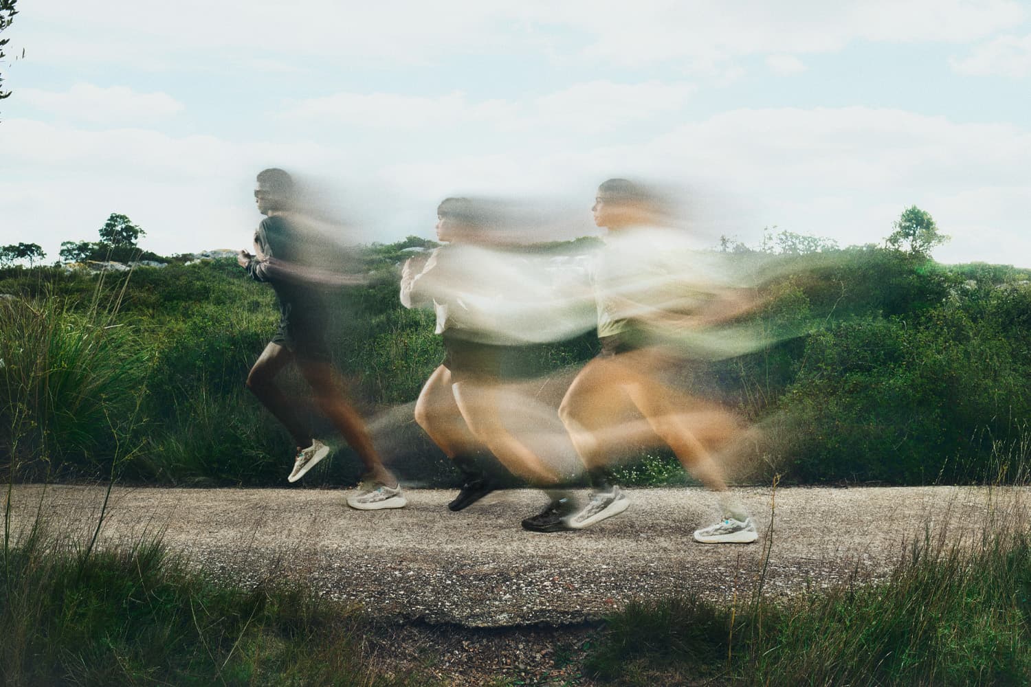 Three people running on a gravel road