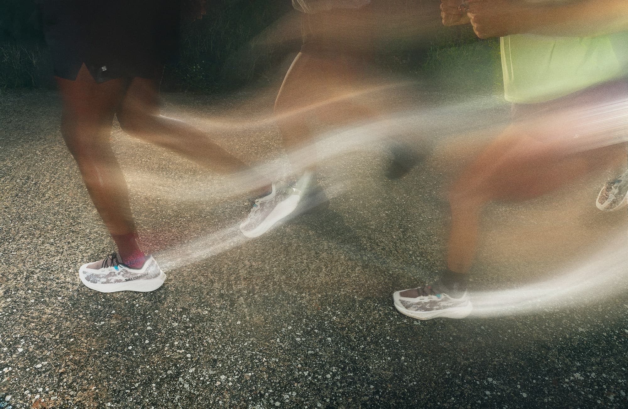 Blurred image of people running on a textured path, emphasizing movement, with white sneakers in focus.