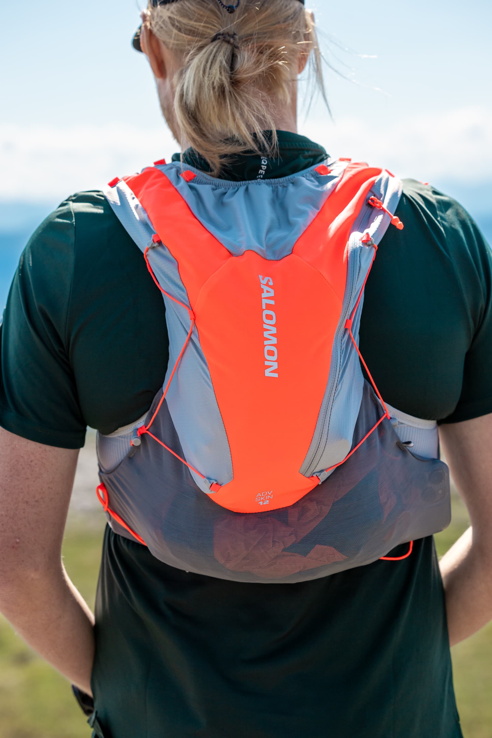 Person wearing a bright orange and gray running backpack.