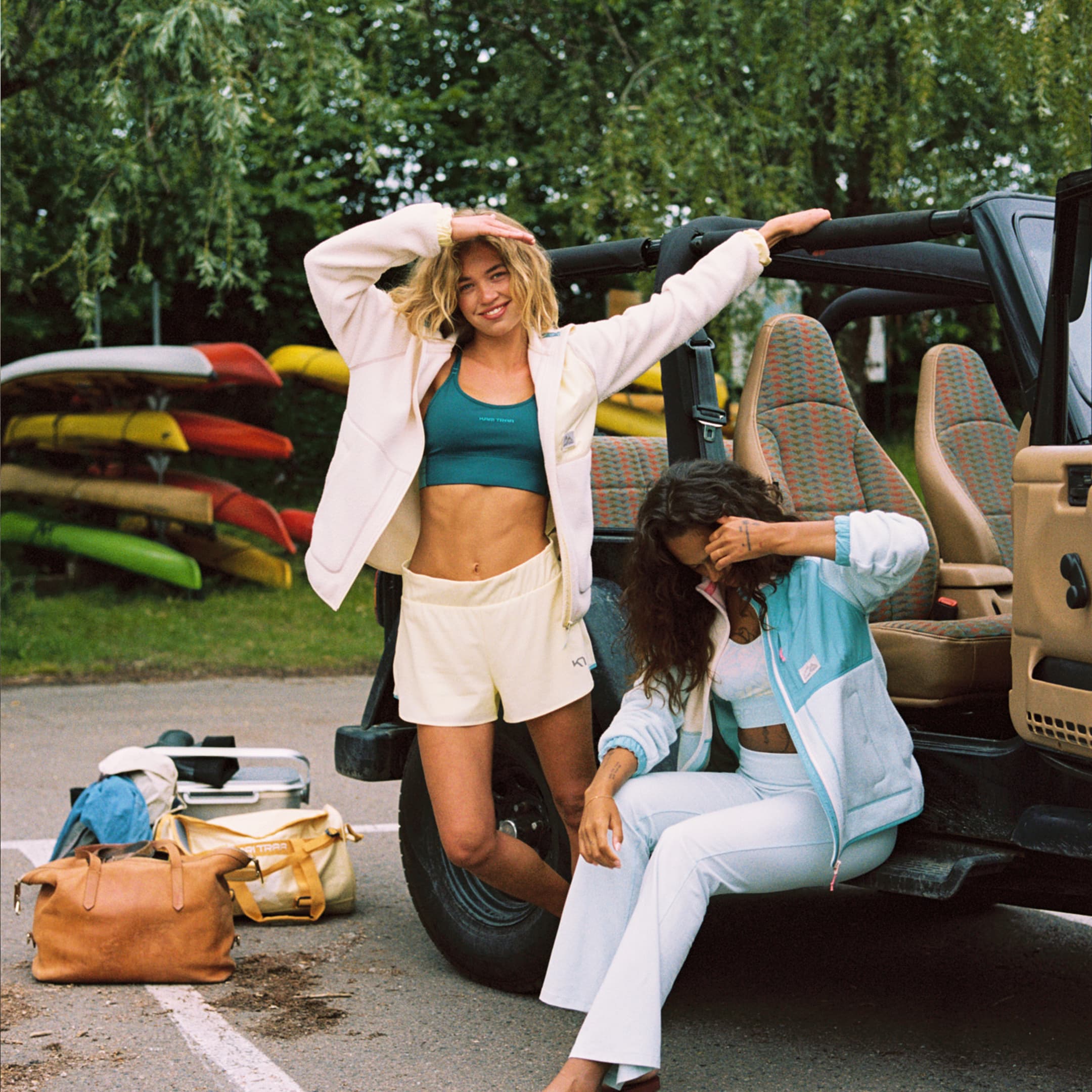 Smiling woman dressed in Kari Traa leaned against a vehicle with a forest in the backgorund