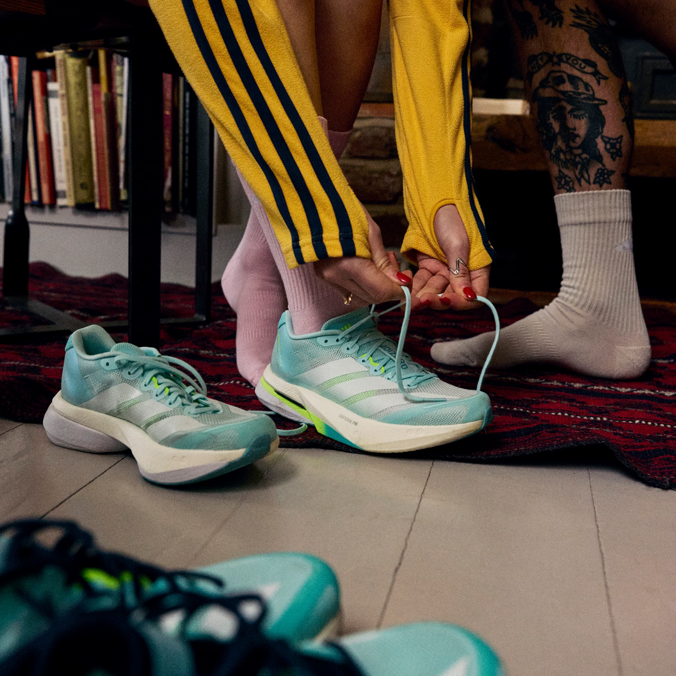Person tying a pair of adidas shoes