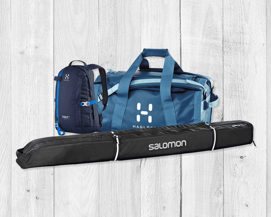 Blue duffel bag, blue backpack, and black ski bag on a light wooden background.