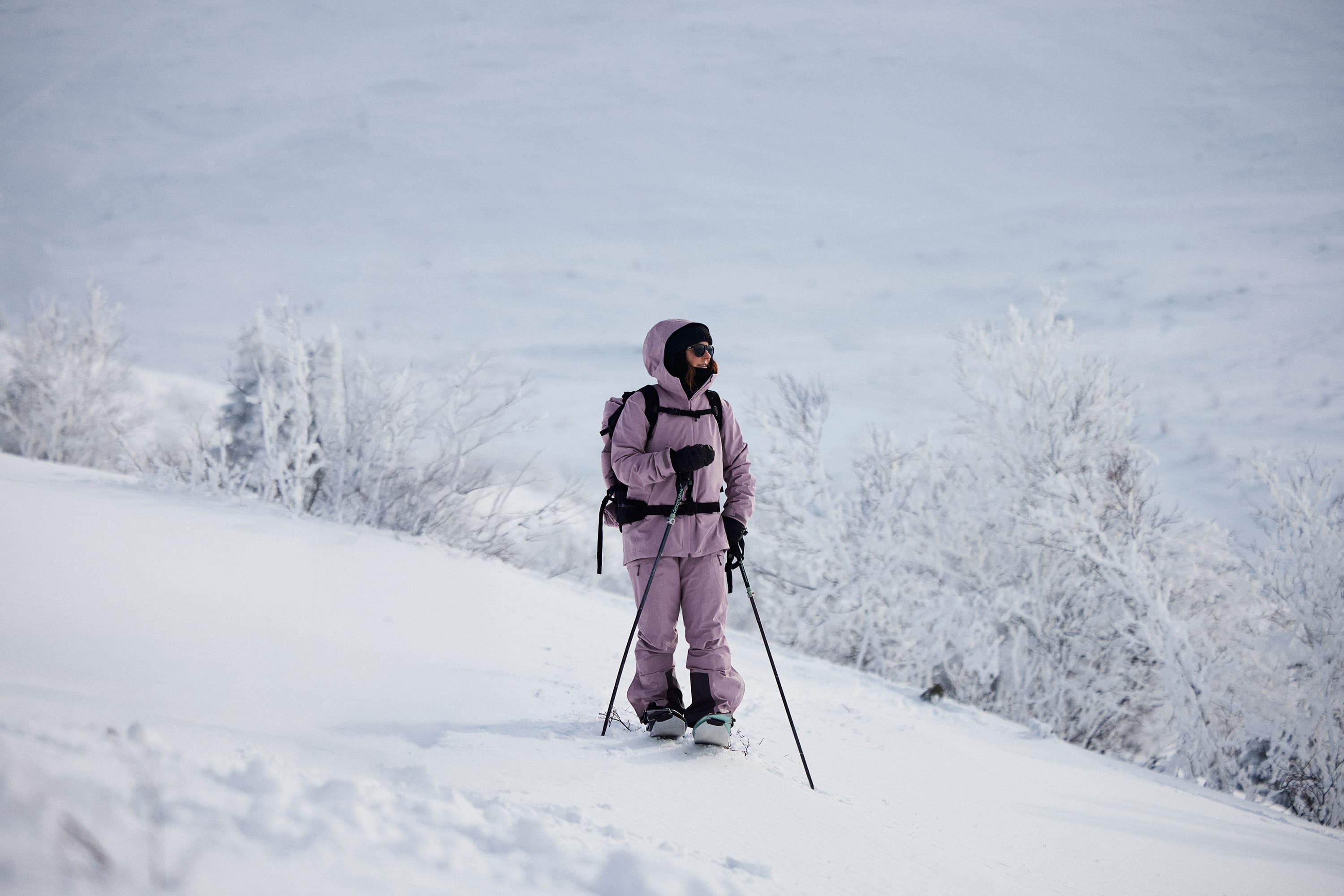 Woman in purple ski clothes standing in a snowy landscape on a splitboard